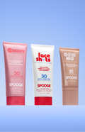 Five SPOOGE sunscreen tubes in assorted colors are lined up against a light blue gradient background. The tubes include shades of white, pink, red, brown, and blue, each with different brand graphics and SPF levels ranging from 30 to 50.